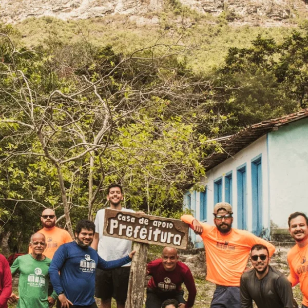 Grupo de amigos tiram foto na casa de apoio da prefeitura, com casa de nativo e vegetação ao fundo, trekking do vale do pati
